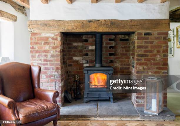 armchair and fireplace in living room - wood burning stove stockfoto's en -beelden