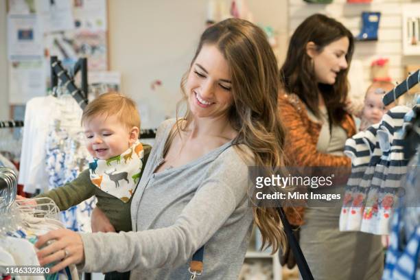 caucasian mother and baby son shopping in clothing store - baby products photos et images de collection