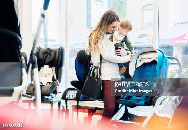 caucasian mother and baby son shopping in stroller store - baby products stock pictures, royalty-free photos & images