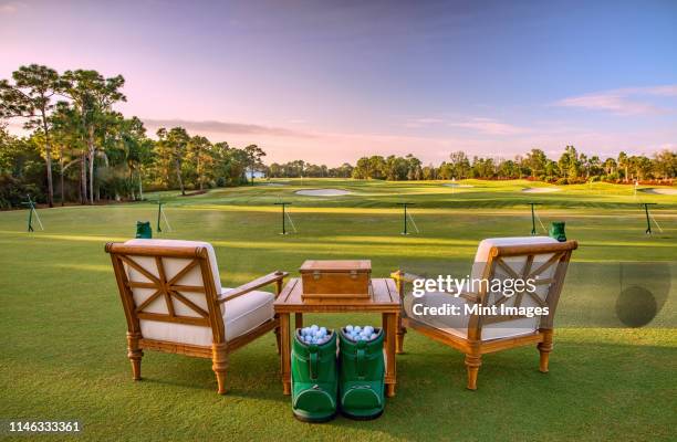 chairs and golf balls on driving range - driving range stock pictures, royalty-free photos & images