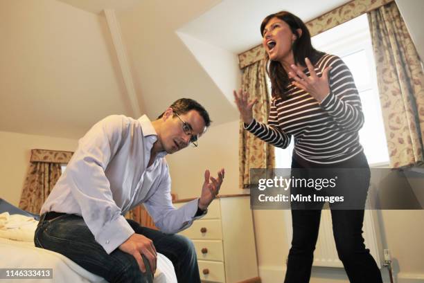 caucasian couple arguing in bedroom - mêlée stock-fotos und bilder