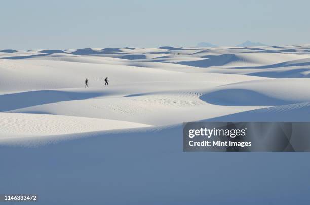 distant people walking on snowy landscape - new mexico stock pictures, royalty-free photos & images
