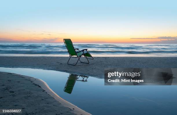 lounge chair on beach at sunset - ヒューロン湖 ストックフォトと画像