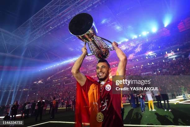 Galatasaray's French-Moroccan forward Younes Belhanda holds the trophy during a victory ceremony after the football club won the Turkish Super League...