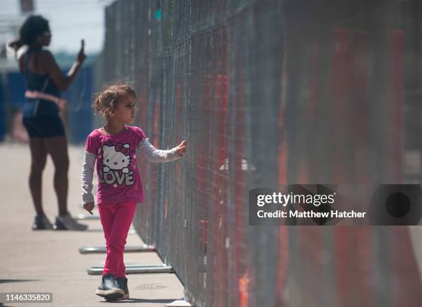 Three-year-old Laylani Jeniya-Smith Edgecomb looks through the chainlink fence that separates counter protesters from a protest against a rally held...