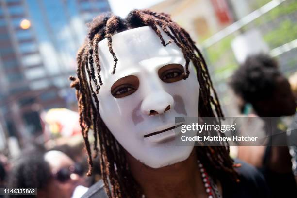 Masked counter-protester walks through a large crowd of other counter demonstrators during a protest against a rally held by the KKK affiliated group...