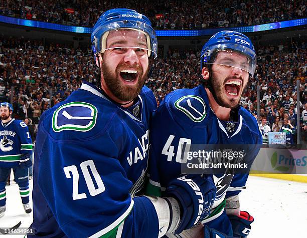 Chris Higgins and teammate Maxim Lapierre of the Vancouver Canucks celebrate their 3-2 overtime win over the San Jose Sharks in Game Five of the...