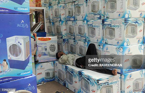 Worker sleeps on stacked up boxes of new air coolers for sale at a market in New Delhi on May 25 as temperatures reached 43 degrees Celsius. A torrid...