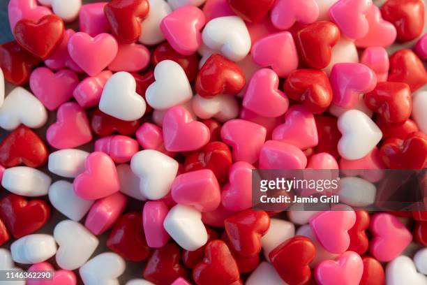 pile of heart shaped candy - candy hearts stock pictures, royalty-free photos & images