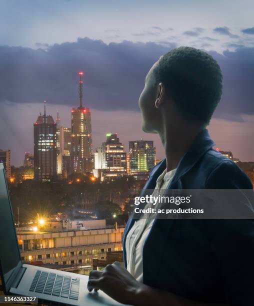 businesswoman holding laptop by city skyline at sunset in nairobi, kenya - kenya business stock pictures, royalty-free photos & images