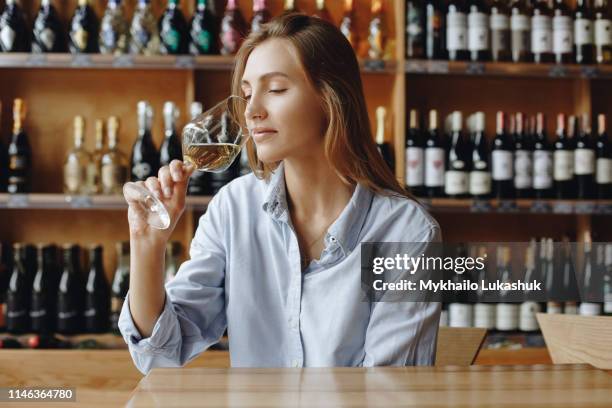 young woman sniffing glass of white wine - wijn proeven stockfoto's en -beelden