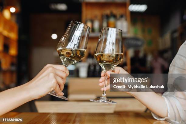 hands of women toasting with glasses of white wine - wine tasting stock-fotos und bilder