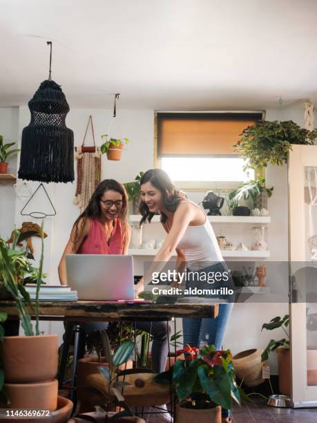 Two young women looking at laptop computer in workplace