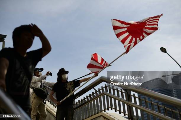 Right-wing, nationalist protester holds an Imperial Japanese army flags towards demonstrators during a demonstration against the U.S president Donald...