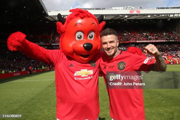 David Beckham of Manchester United '99 Legends celebrates with Fred the Red at the end of the 20 Years Treble Reunion match between Manchester United...