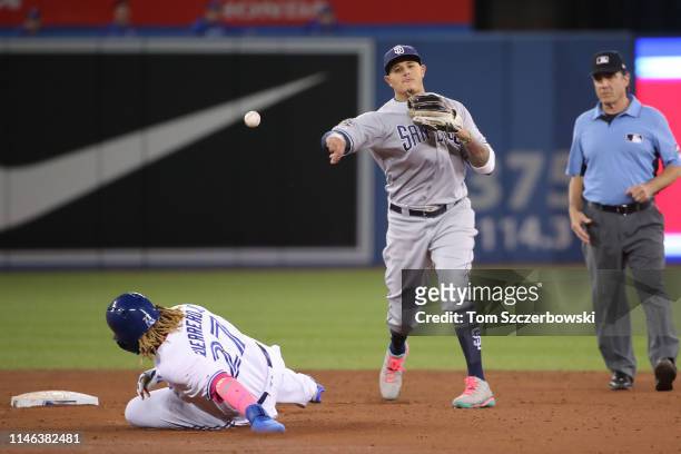 Manny Machado of the San Diego Padres turns a double play over Vladimir Guerrero Jr. #27 of the Toronto Blue Jays at second base in the third inning...