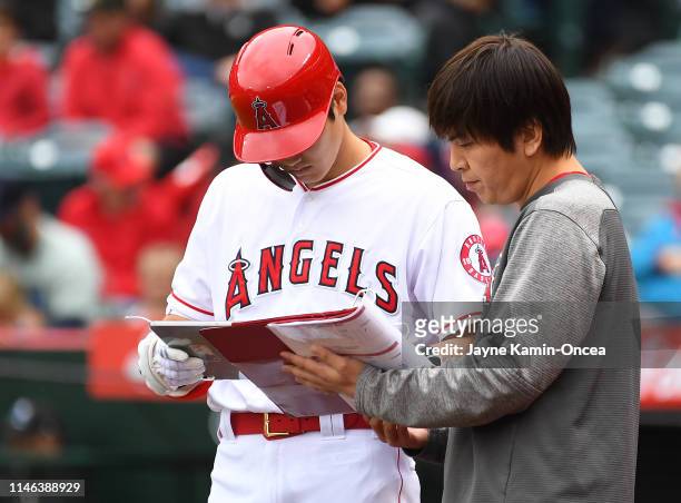 Shohei Ohtani of the Los Angeles Angels of Anaheim hit a sacrifice fly after going over notes with interpreter Ippei Mizuhara after a pitching change...