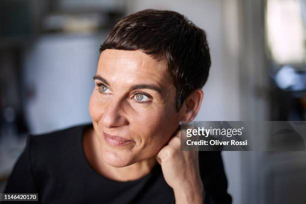 portrait of smiling short-haired woman at home looking away - mature brunette woman stockfoto's en -beelden