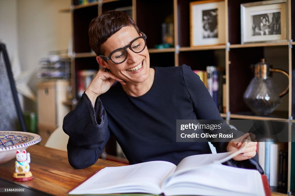 Smiling woman reading a book at home