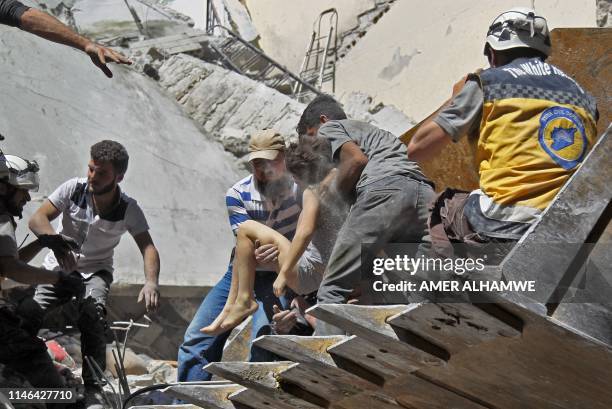 White Helmet rescue volunteers and civilians rescue a child from the rubble of a building destroyed during an air strike by Syrian regime forces and...