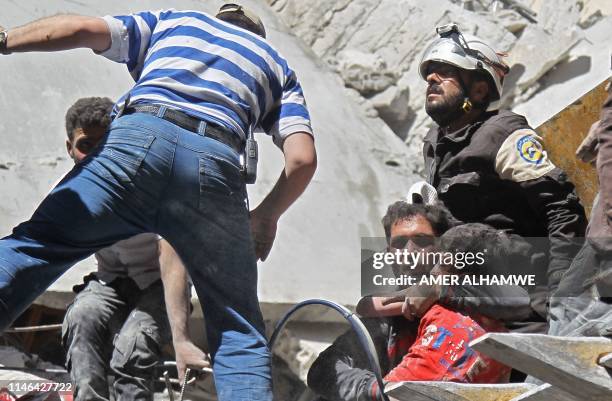 White Helmet rescue volunteers and civilians rescue a child from the rubble of a building destroyed during an air strike by Syrian regime forces and...