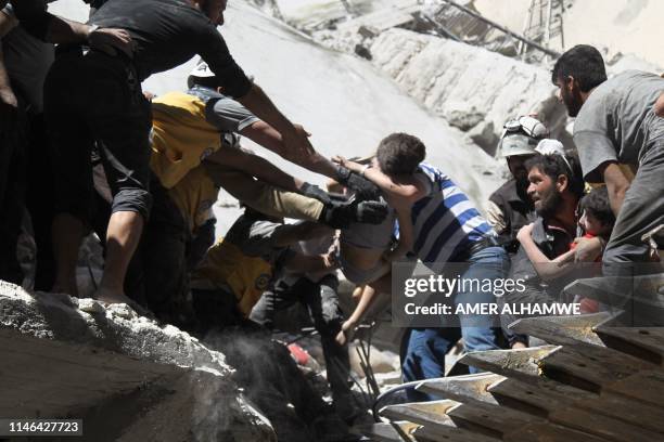 White Helmet rescue volunteers and civilians rescue a child from the rubble of a building destroyed during an air strike by Syrian regime forces and...