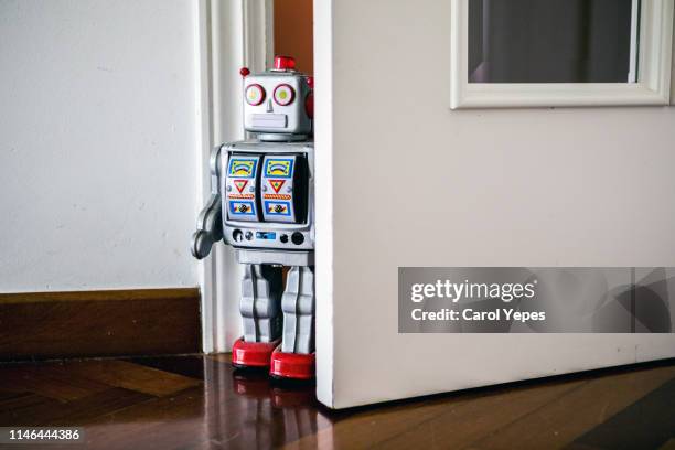 little tin robot peeking from kids door - wind up toy foto e immagini stock