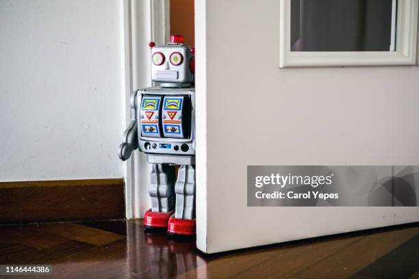 little tin robot peeking from kids door - opwindspeeltje stockfoto's en -beelden