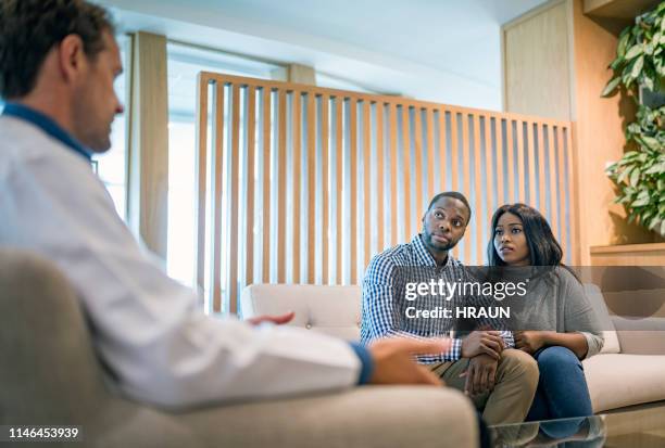 worried young couple listening to doctor in a hospital. - infertility doctor stock pictures, royalty-free photos & images