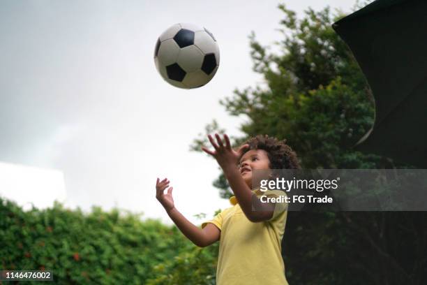 young boy throwing a soccer ball to the air - throwing stock pictures, royalty-free photos & images