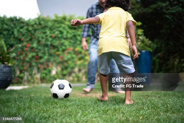 vater und sohn spielen fußball im hinterhof - backyard football stock-fotos und bilder