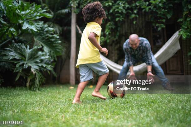 vater und sohn spielen fußball im hinterhof - backyard football stock-fotos und bilder