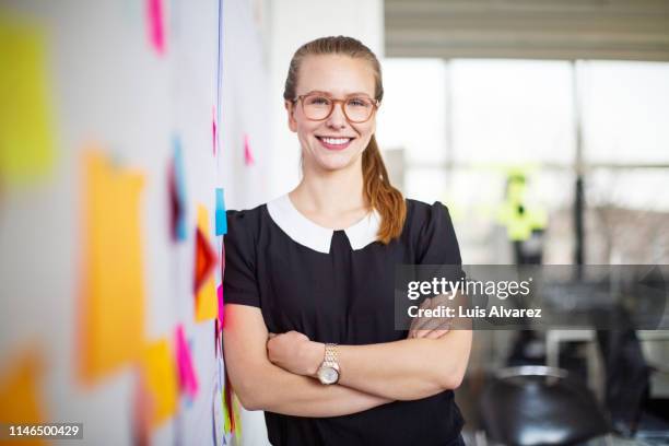 smiling woman standing in office - woman whiteboard stock-fotos und bilder