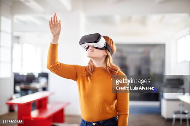 curious businesswoman using vr goggles - réalité virtuelle photos et images de collection