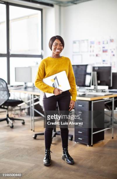 businesswoman with laptop in office - black woman standing stock-fotos und bilder