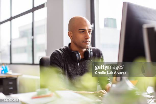 business man working on desktop pc in office - completely bald stock photos et images de collection