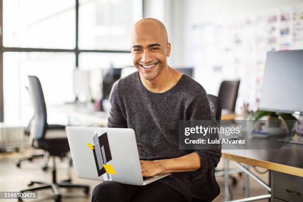 smiling businessman with a laptop in office - easy access chef stock-fotos und bilder