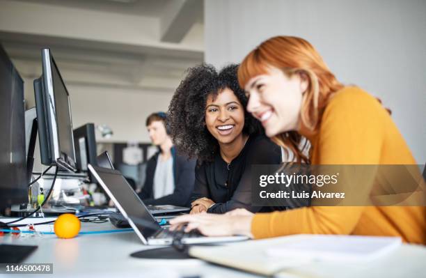 two female colleagues in office working together - souriant parler photos et images de collection