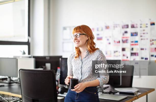 businesswoman having a coffee break in office - rotes haar stock-fotos und bilder