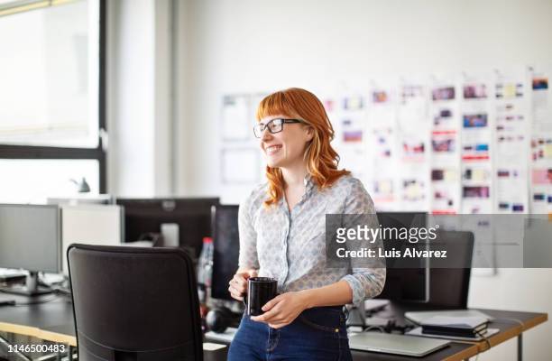businesswoman having a coffee break in office - tevreden stockfoto's en -beelden