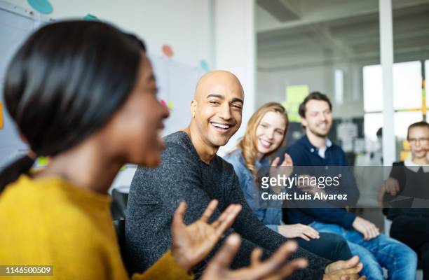 business team smiling during a meeting - multikulturelle gruppe stock-fotos und bilder