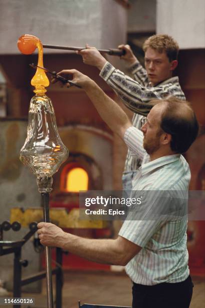 Glassworkers attach a base with molten glass to a vase at the Tyrone crystal factory, County Tyrone, Ireland circa 1987.