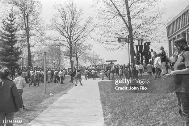 View along a pathway outside Taylor Hall where a students and faculty who hold hands in a circle, inside of which an injured student is loaded into...