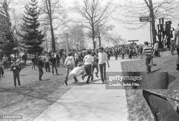 View of paramedics and students as they run past Taylor Hall, carrying a stretcher, after the Ohio National Guard opened fire on antiwar protesters...