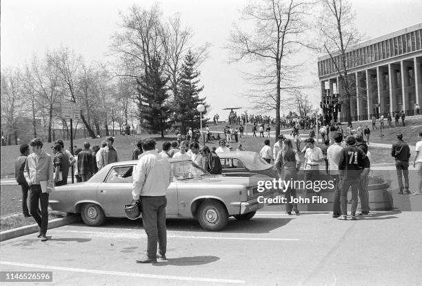 View of students gathered around a parked car with broken windows caused by bullets after the Ohio National Guard opened fire on antiwar protesters...
