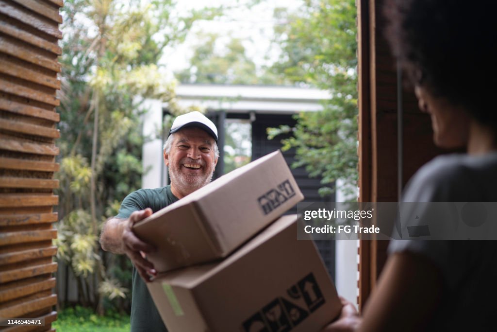 Courier entregando cajas a una mujer joven