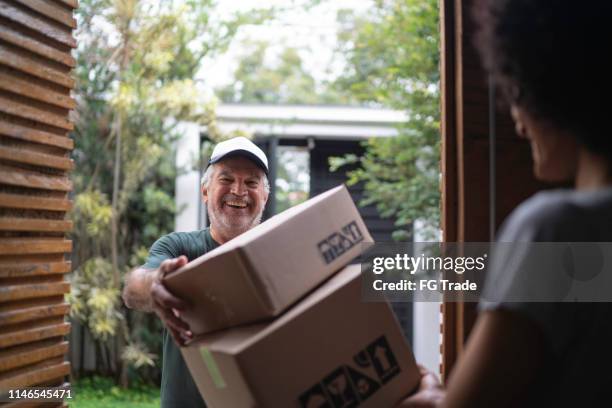 courier leveren dozen aan een jonge vrouw - delivery driver stockfoto's en -beelden