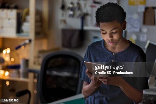 teen boy plays game on digital tablet at home - boy using ipad imagens e fotografias de stock