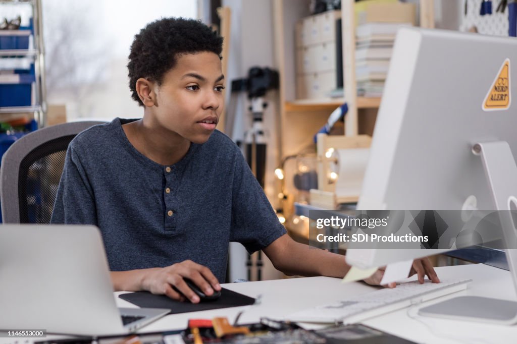 Teen boy plays video game on home computer