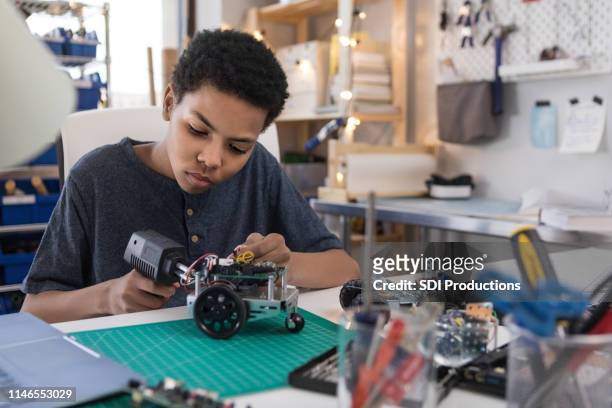 tiener jongen soldeer draden te bouwen robot - school building stockfoto's en -beelden